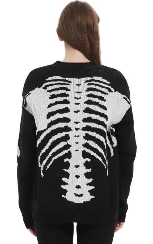A woman viewed from the back wearing a black knit sweater with a large white rib cage graphic across the back, against a plain light gray studio background.