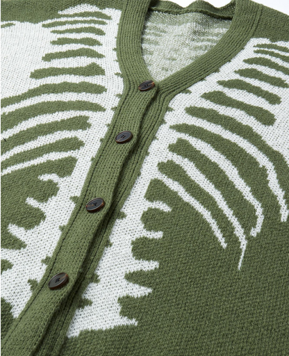 Close-up of a knit cardigan sweater with an olive green and white ribbed pattern, featuring a V-neck and dark brown buttons.