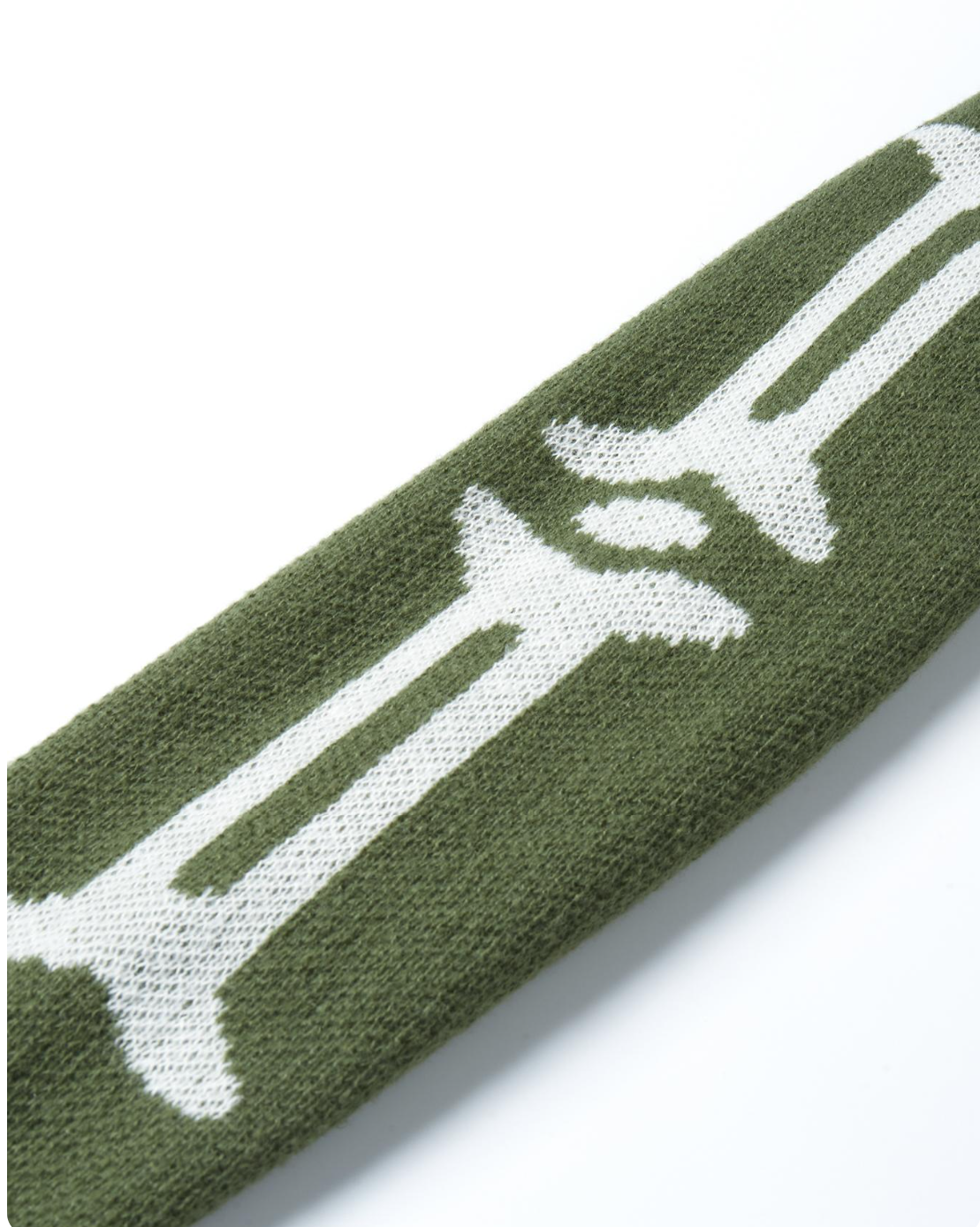 Close-up of a knitted sleeve or cuff in olive green with a large white knit graphic running diagonally across it, shown on a clean white background.